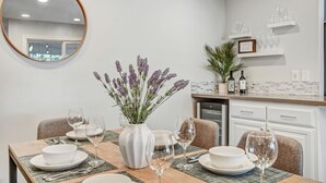 A dining area with a table set for four, a vase of flowers, and a kitchen in the background. - Escape to Wine Country with Friends & Family (Santa Rosa)