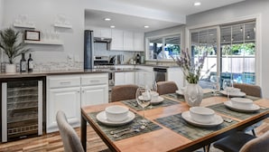 A modern kitchen with white cabinets, a dining area with a wooden table, and a view of the outdoors. - Escape to Wine Country with Friends & Family (Santa Rosa)