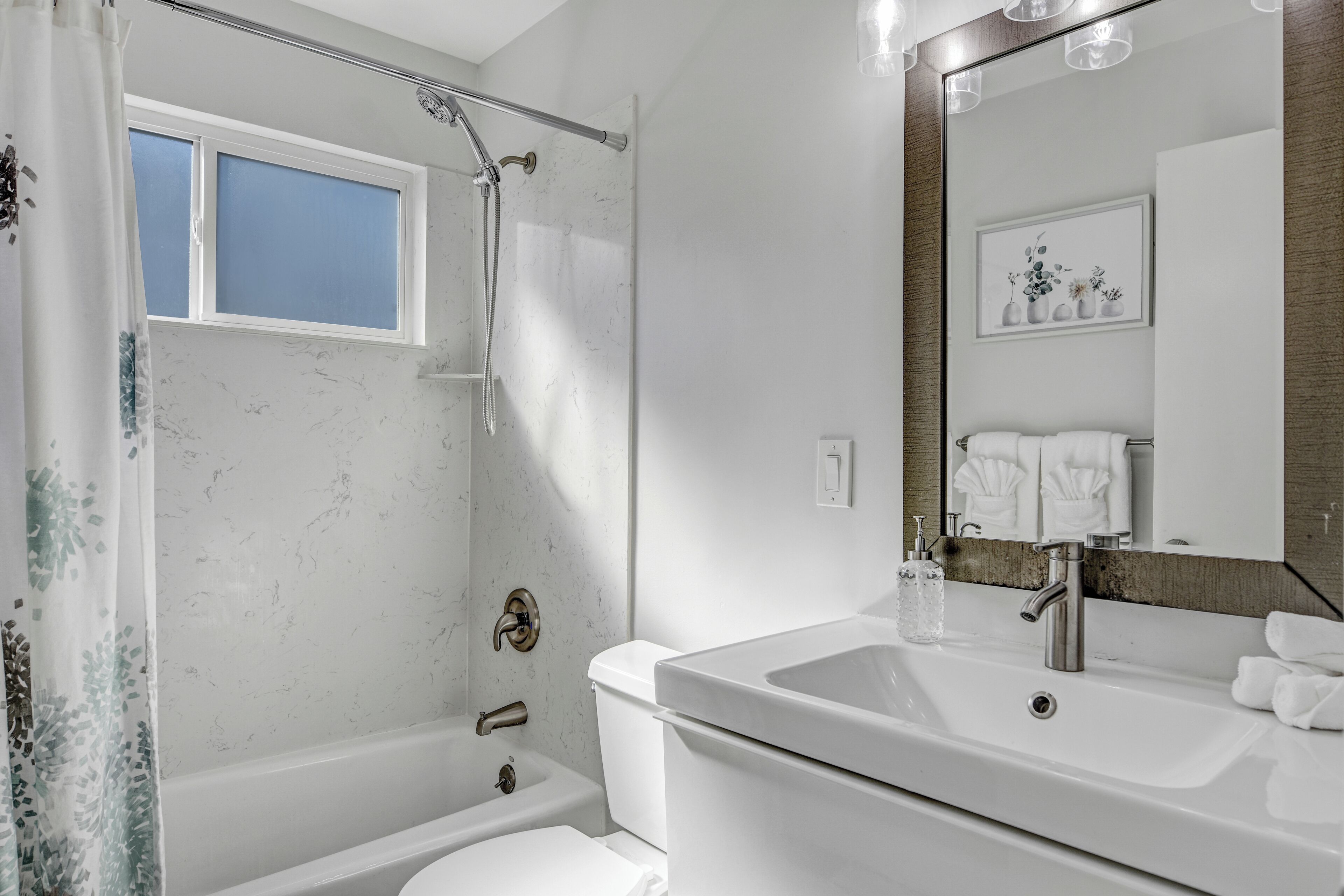 Une salle de bain moderne équipée d’une baignoire, d’une douche, d’un lavabo et de toilettes.