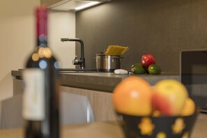 Uma cozinha com um prato de espaguete, uma garrafa de vinho e uma tigela de fruta.