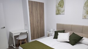 Un dormitorio con cama, escritorio, silla y armario.