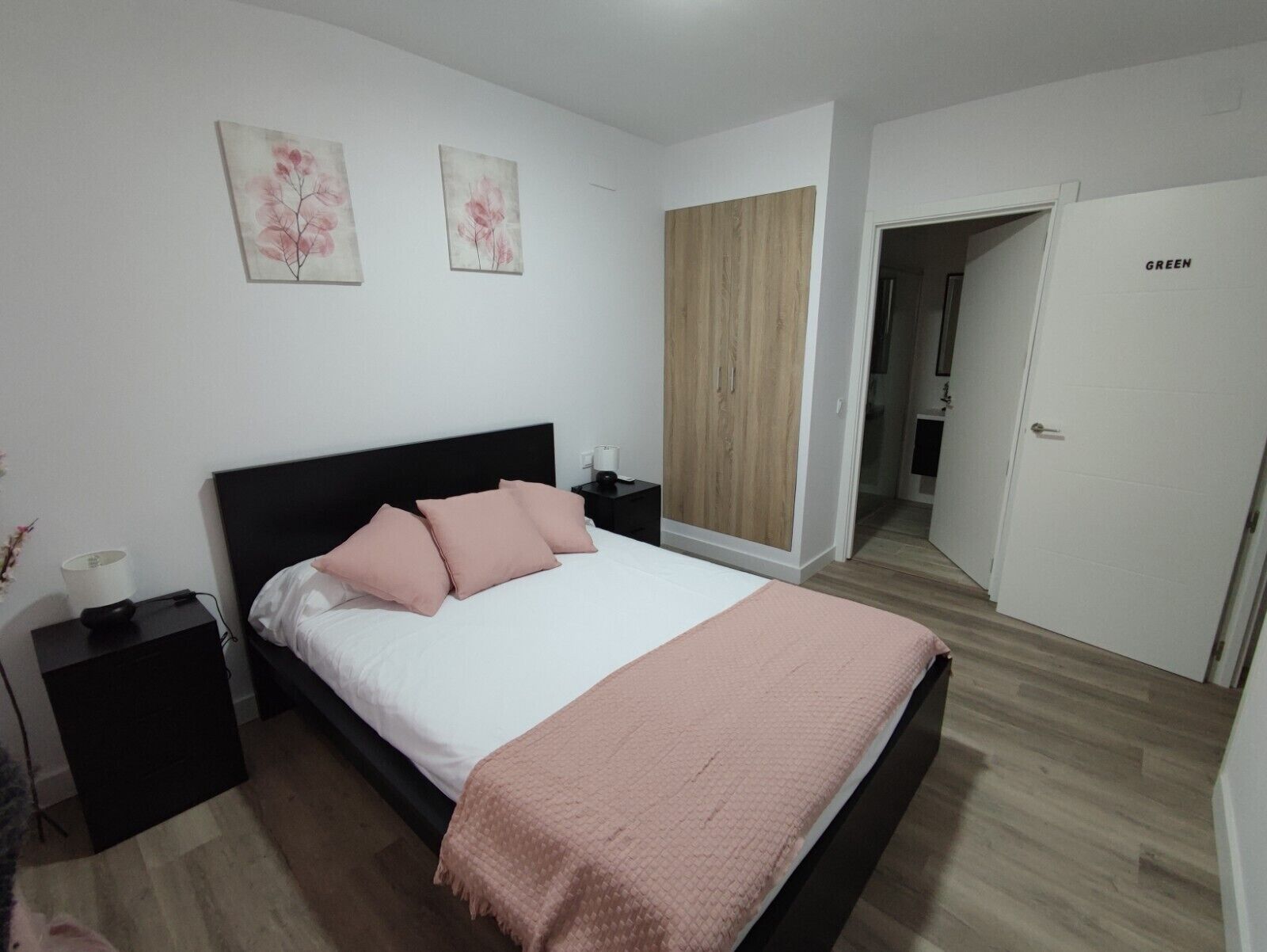 A bedroom with a bed, two nightstands, a wardrobe, and a door labeled "GREEN".