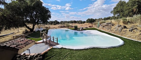 A swimming pool with a wooden deck and a grassy area.