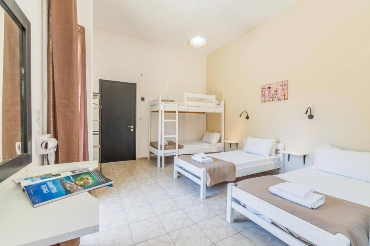 Habitación de hotel con literas, un escritorio con una revista, una puerta y una pared con un cuadro.