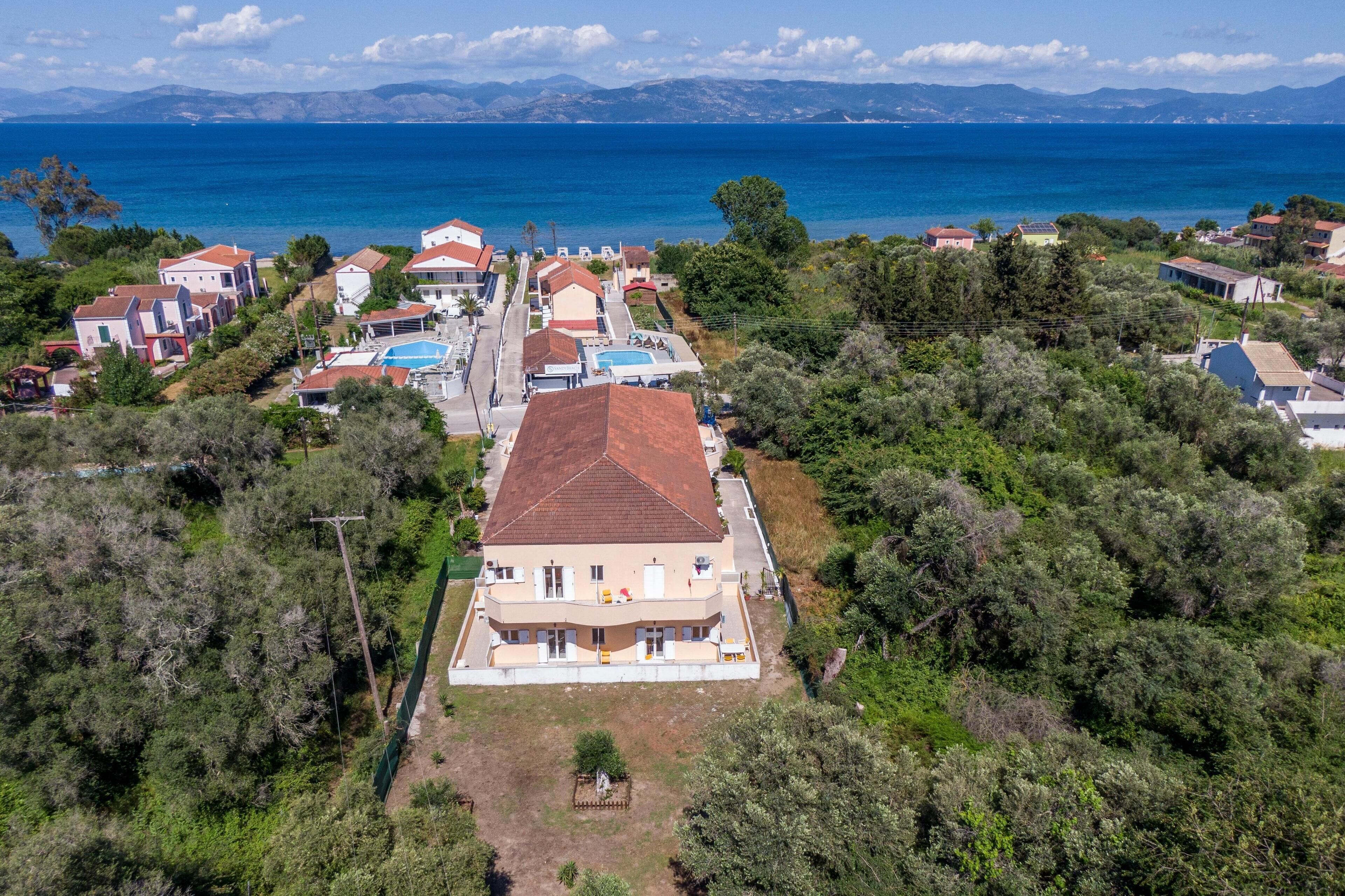 A coastal residential area with houses, a swimming pool, and a view of the sea.