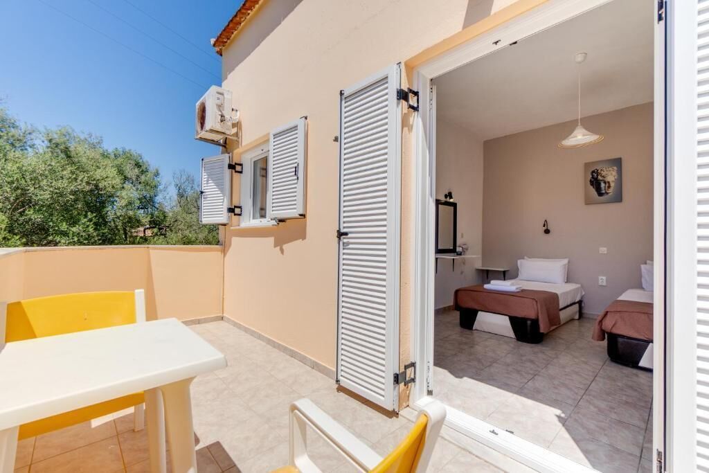 Una habitación con cama, mesita de noche y ventana con contraventanas.