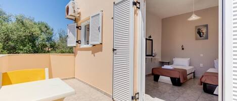 Una habitación con cama, mesita de noche y ventana con contraventanas.