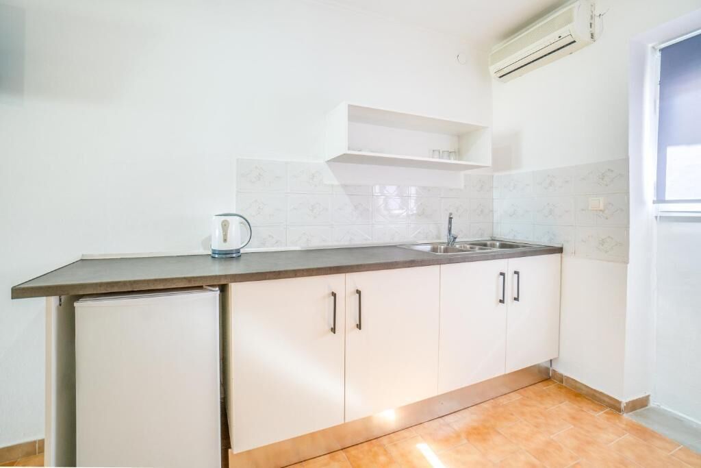 Una cocina compacta con refrigerador, pileta y encimera.
