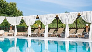 A pool area with white drapes, sun loungers, and a clear blue pool. - Saint Peter Bay Aparthotel by Konnect (Corfu)
