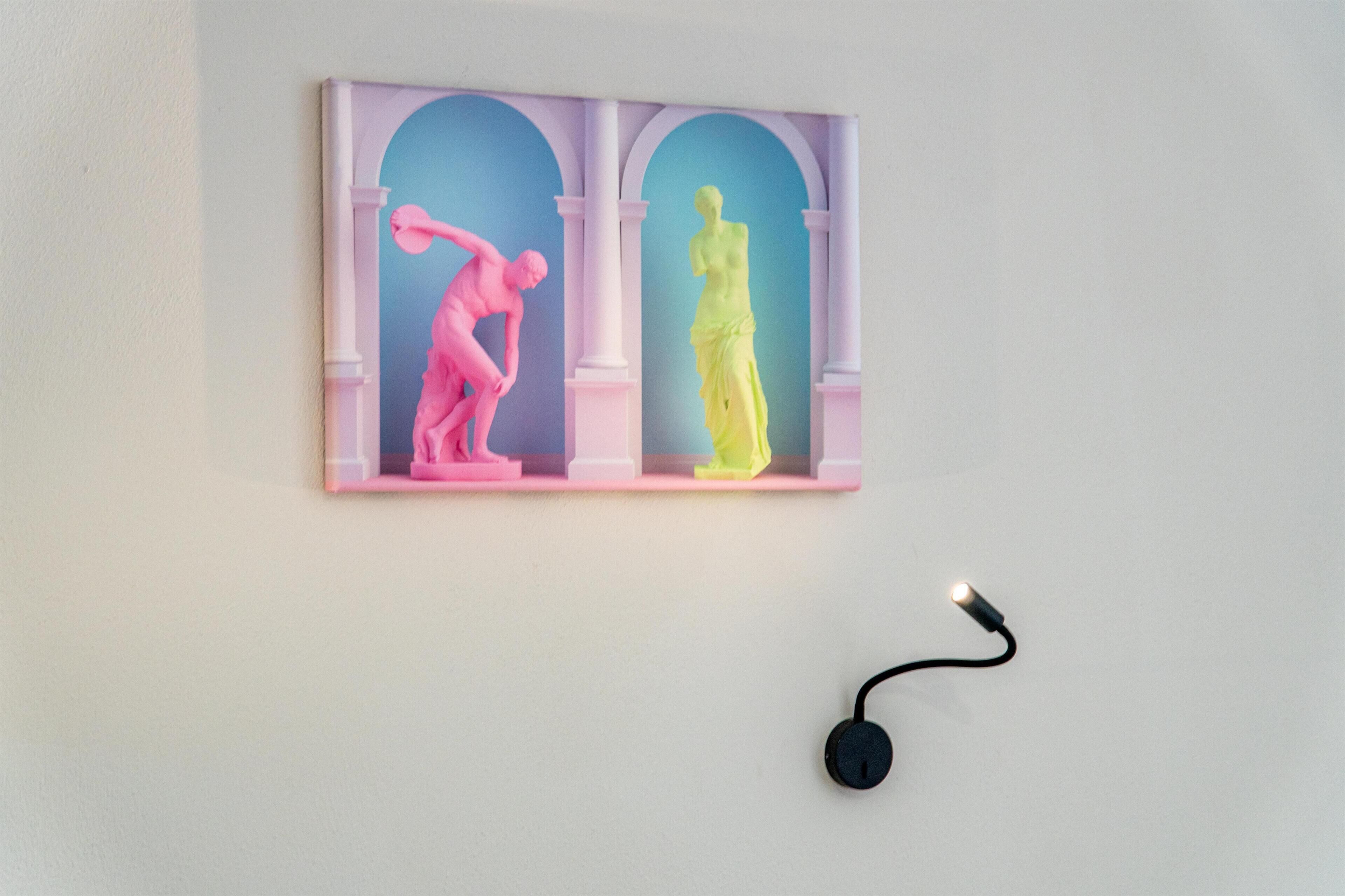 Una obra de arte en la pared que muestra dos figuras en rosa y amarillo, enmarcada por arcos, con un enchufe debajo.