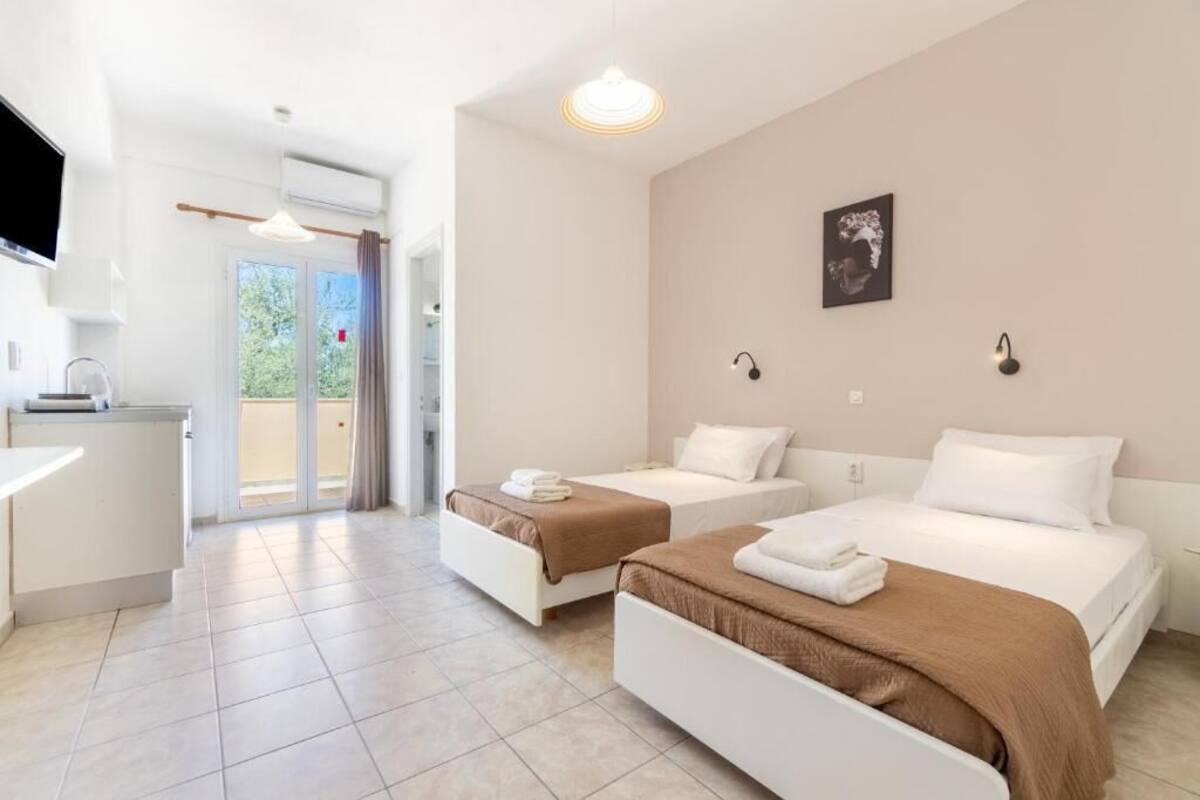 Habitación de hotel con dos camas, kitchenette y un ventanal grande.