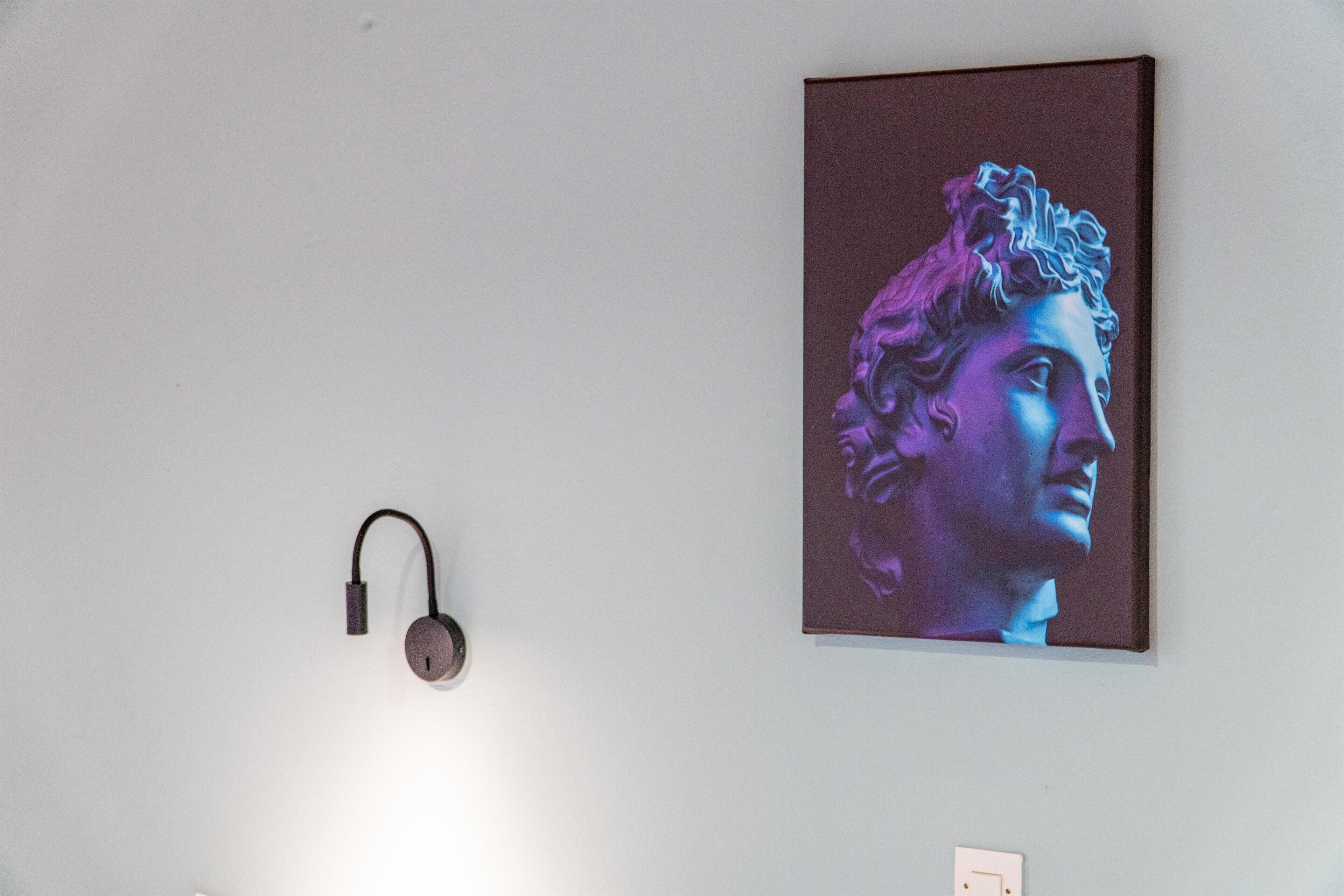 A wall with a painting of a classical figure and a modern light fixture.
