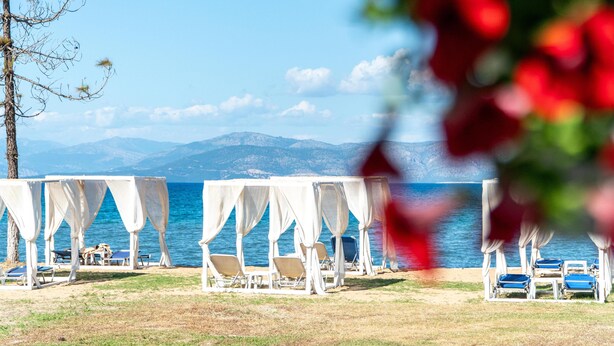 A beachside view with white canopies and lounge chairs. - Saint Peter Bay Aparthotel by Konnect (Corfu)