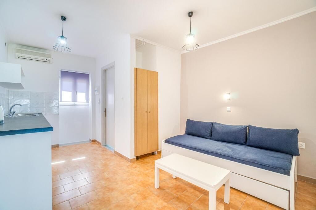 A modern apartment with a kitchenette, a wooden wardrobe, a blue sofa, and a white coffee table.