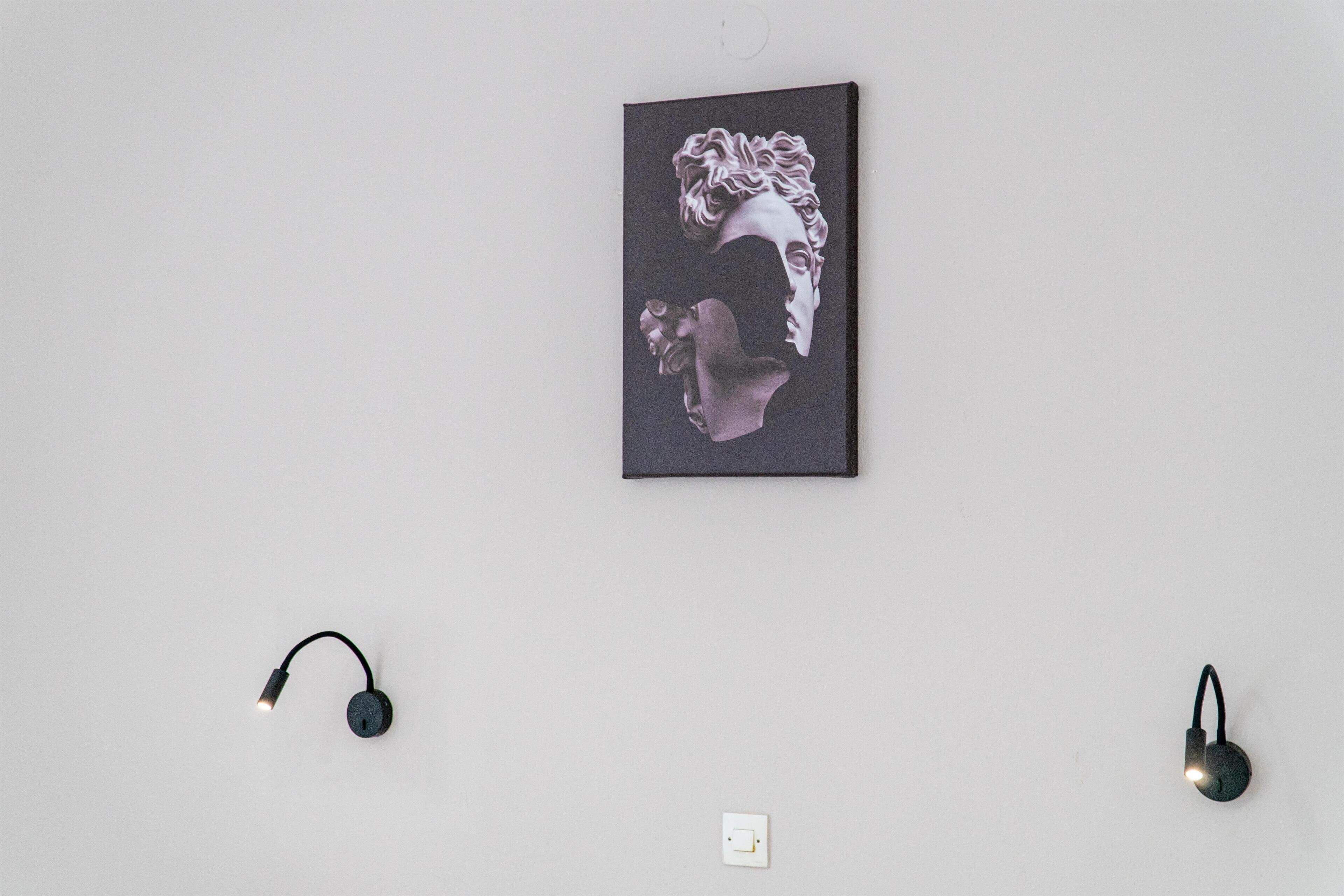 A wall with a framed artwork and two wall-mounted speakers.