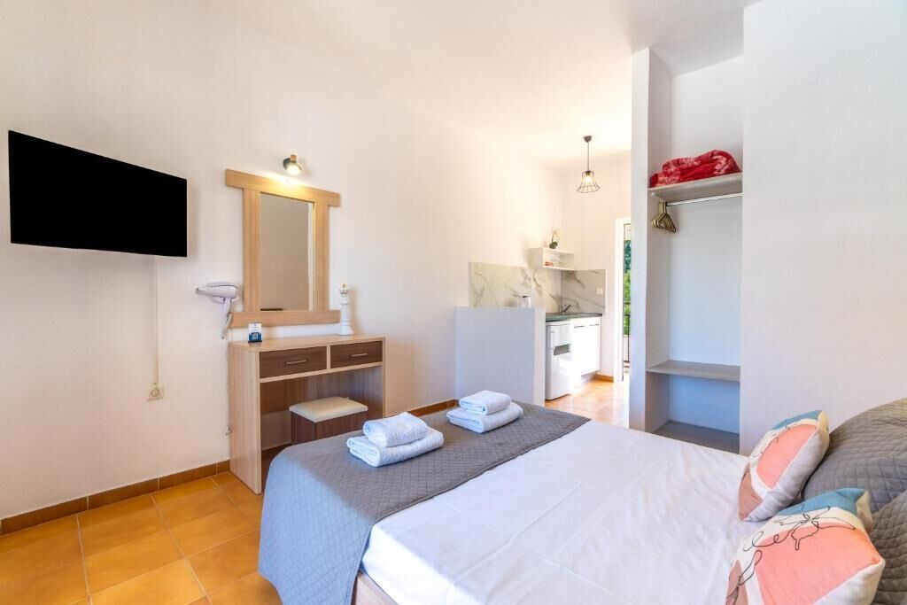 Ein Schlafzimmer mit Bett, Nachttisch, Spiegel, Kleiderschrank und Wandfernseher.