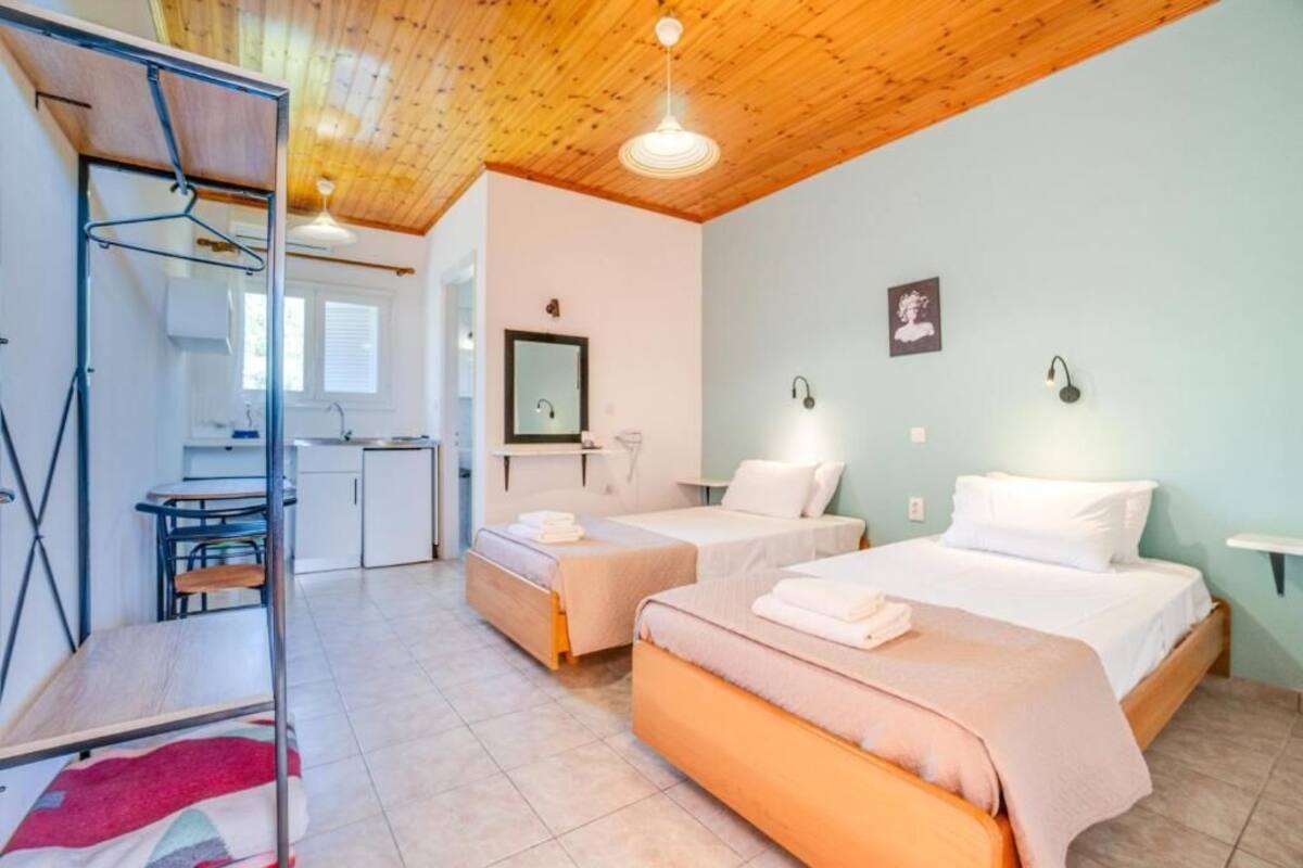 Una habitación con dos camas, un escritorio y un perchero.