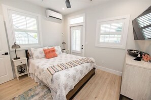 A bedroom with a bed, nightstands, a dresser, and a window with blinds.