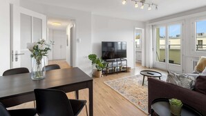 A modern living room with a dining table, chairs, a TV, and a sofa. - Cozy Central Lucerne Apartment with Balcony (Luzern)
