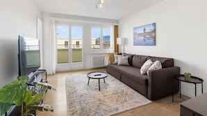 A living room with a sofa, a coffee table, a TV, and a plant. - Cozy Central Lucerne Apartment with Balcony (Luzern)