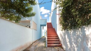 Une ruelle étroite avec un escalier rouge menant à un immeuble.