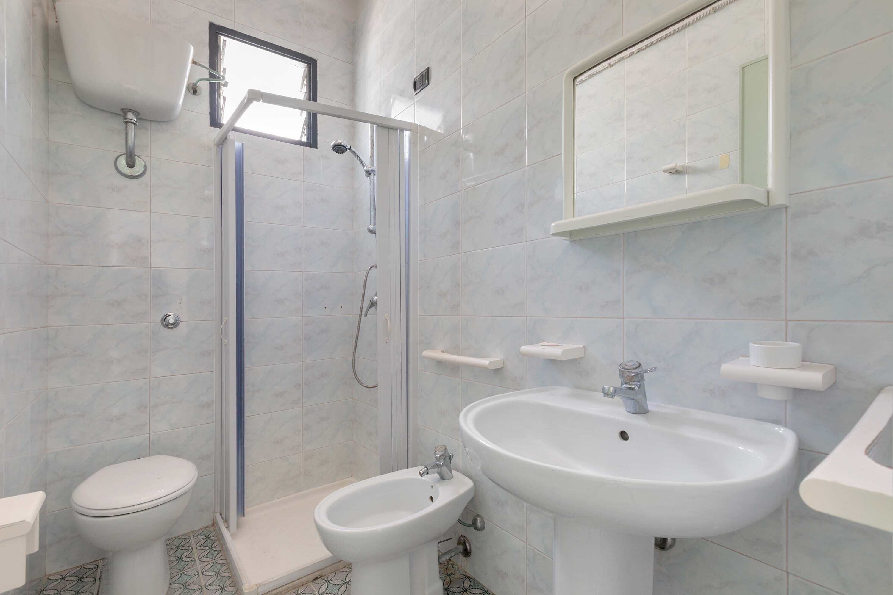 Ein Badezimmer mit Toilette, Bidet, Dusche, Waschbecken und Spiegel.