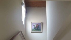 Een trap met een houten leuning en een ingelijst kunstwerk aan de muur.