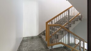 Una escalera con barandilla de madera y balaustradas de metal, que conduce a un piso superior.