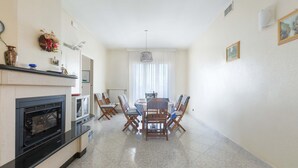 Un área de comedor con una mesa, sillas, chimenea y una ventana con cortinas.