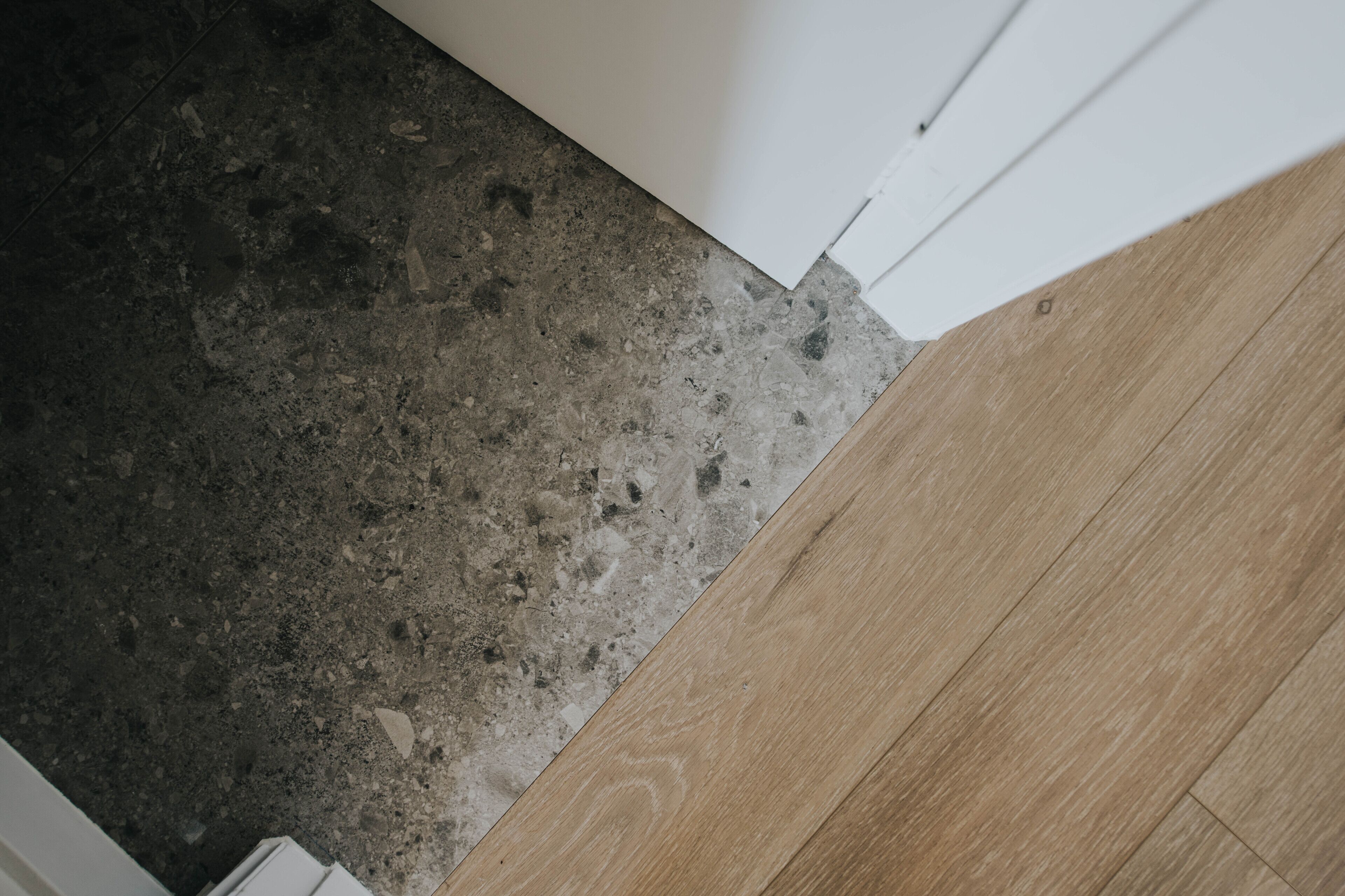 A corner of a room with a concrete floor and a wooden floor.