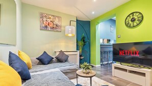 Una sala de estar moderna con un sofá, una mesa de centro, un televisor y una planta en maceta.