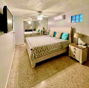 A bedroom with a bed, bedside table, lamp, and a ceiling fan. - Pillars Of The East Beach House (Punta Santiago)