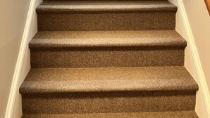 A carpeted staircase with a handrail and a wooden handrail on the right side. - The Krause Historic Eau Claire Home (Eau Claire)
