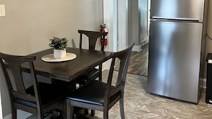 A kitchen with a dining table, chairs, a refrigerator, and a painting on the wall. - The Krause Historic Eau Claire Home (Eau Claire)