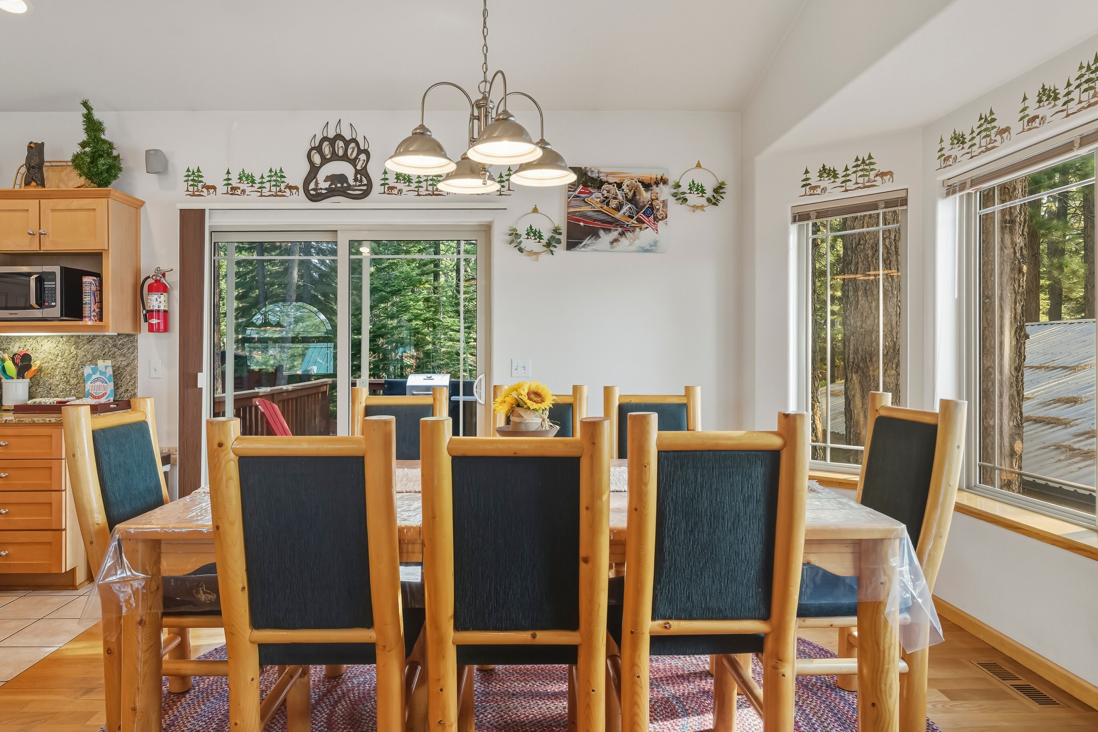 Un comedor con una mesa y sillas de madera, una araña y detalles decorativos en la pared.