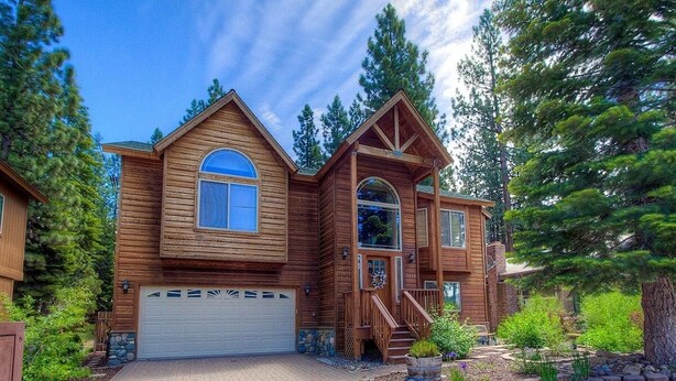 A two-story wooden house with a garage, surrounded by trees and a landscaped garden. - Pine Mountain Paradise 3 Bedroom Home by RedAwning (South Lake Tahoe)