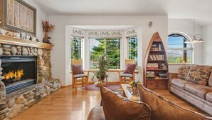 A cozy living room with a stone fireplace, comfortable seating, and a bookshelf. - Pine Mountain Paradise 3 Bedroom Home by RedAwning (South Lake Tahoe)