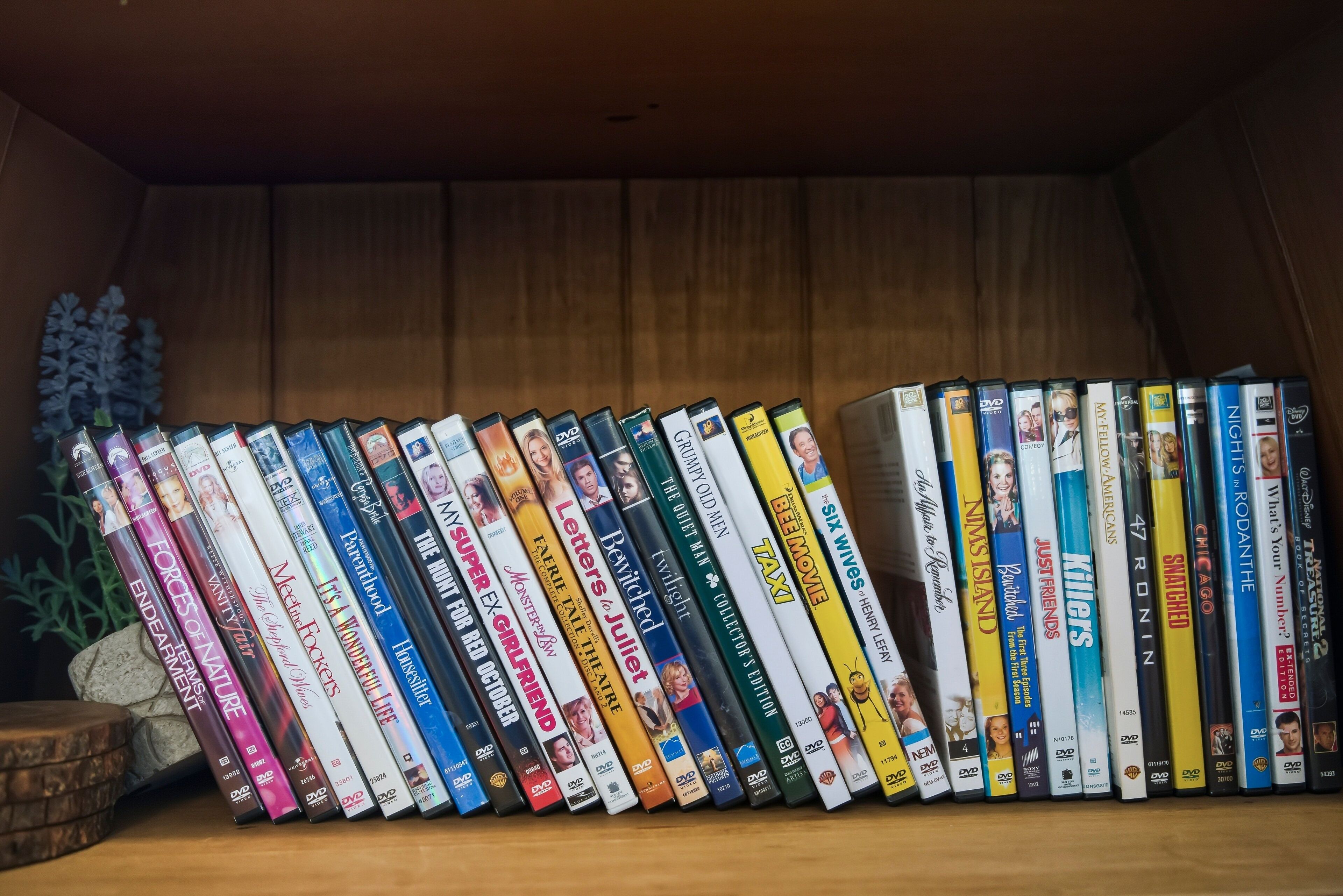 Una col·lecció de DVD en una prestatgeria de fusta.