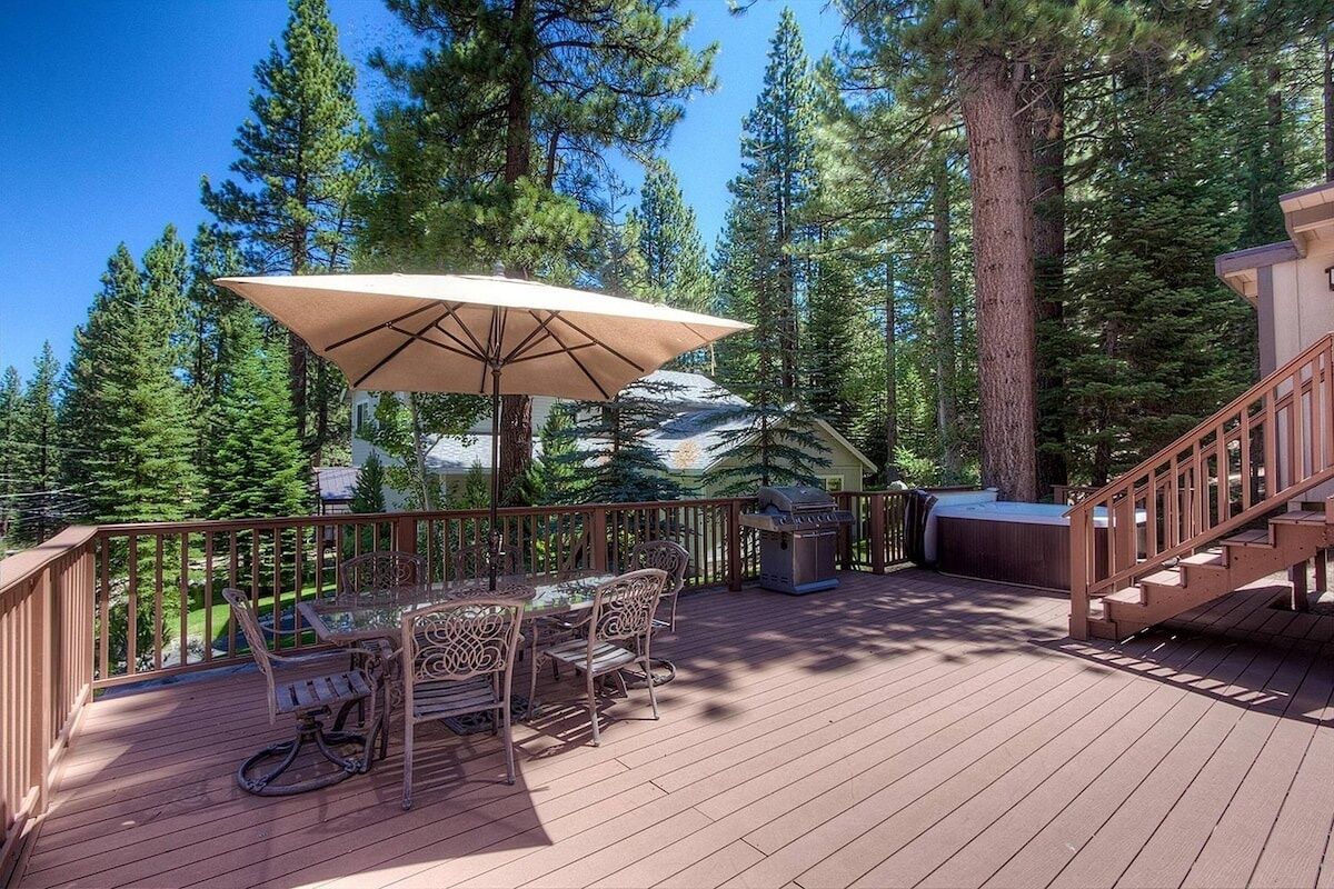 Una terraza de madera con mobiliario exterior, una parrilla y un jacuzzi.