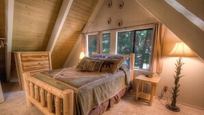 A cozy attic bedroom with a wooden bed, a nightstand, and a lamp.