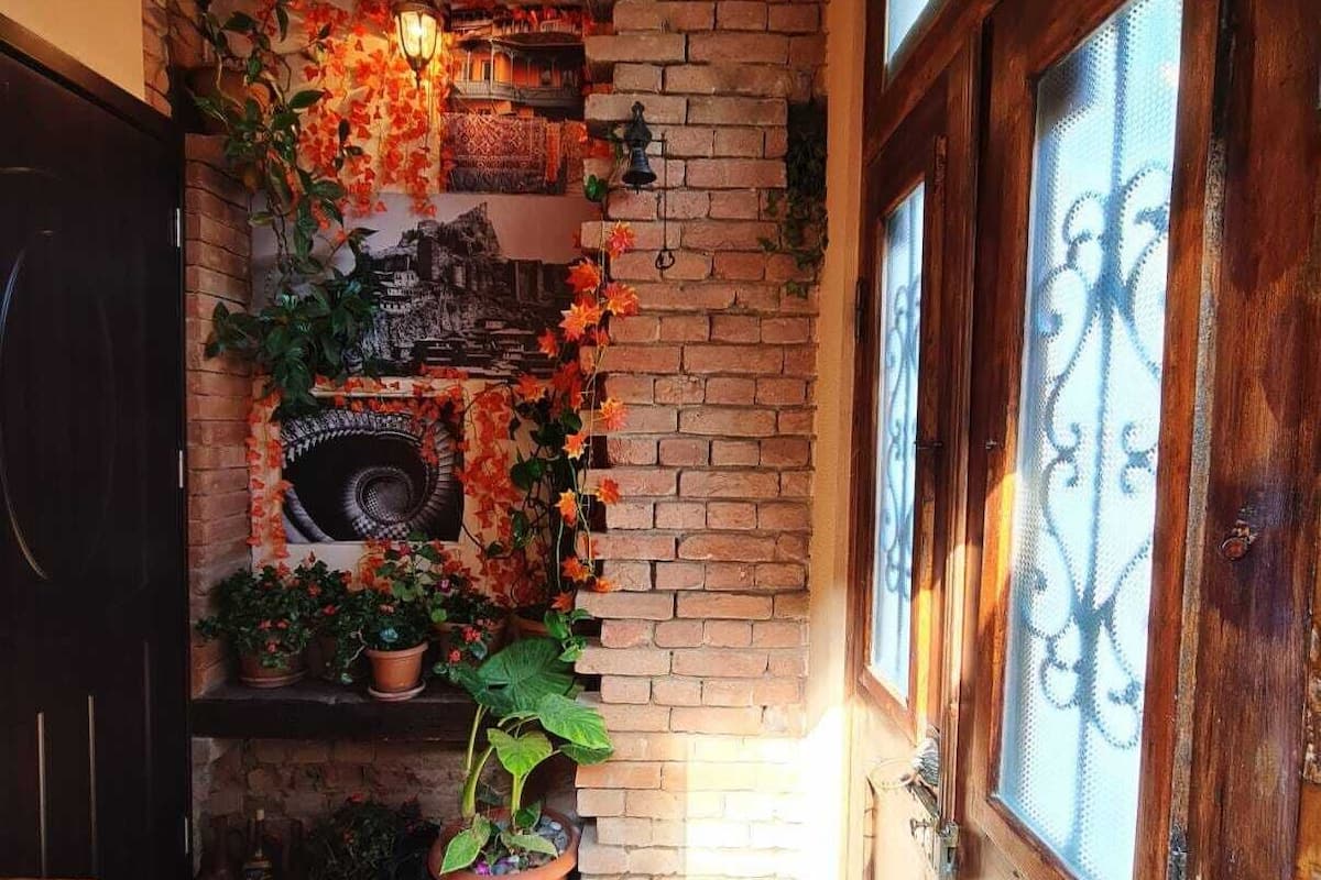 Un intérieur chaleureux avec une cheminée en briques, des bancs en bois et des plantes en pot.