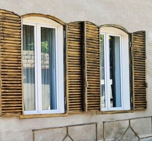 A building facade with three windows featuring wooden shutters.