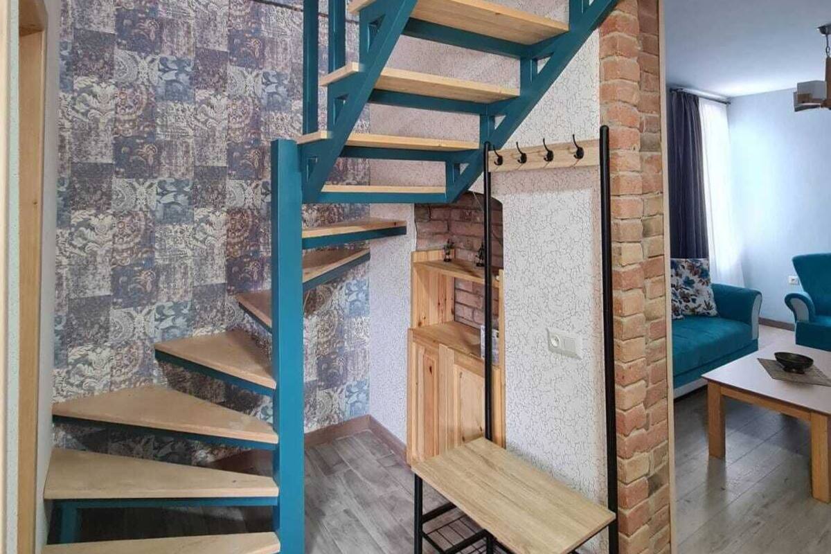 Un escalier en colimaçon agrémenté de touches de bleu, un mur orné de motifs et une colonne en briques dans un espace de vie moderne.