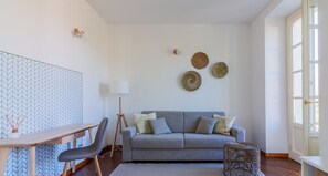 A modern living room with a grey sofa, a wooden coffee table, a standing lamp, and a patterned rug. - Green Rose by Wonderful Italy (Bellagio)