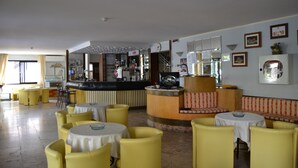 A hotel lobby with yellow seating, a reception desk, and a bar area. - Hotel Rosy (Bellaria-Igea Marina)