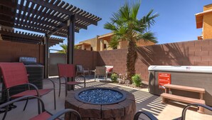 Uma área de estar externa com lareira, assentos e pérgola.