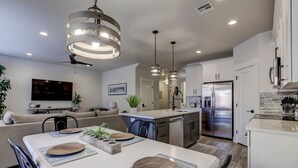 Uma cozinha moderna com ilha central, eletrodomésticos de aço inoxidável e iluminação pendente.