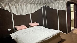 Un dormitori amb un llit gran, un capçal, una tauleta de nit i una taula de nit.