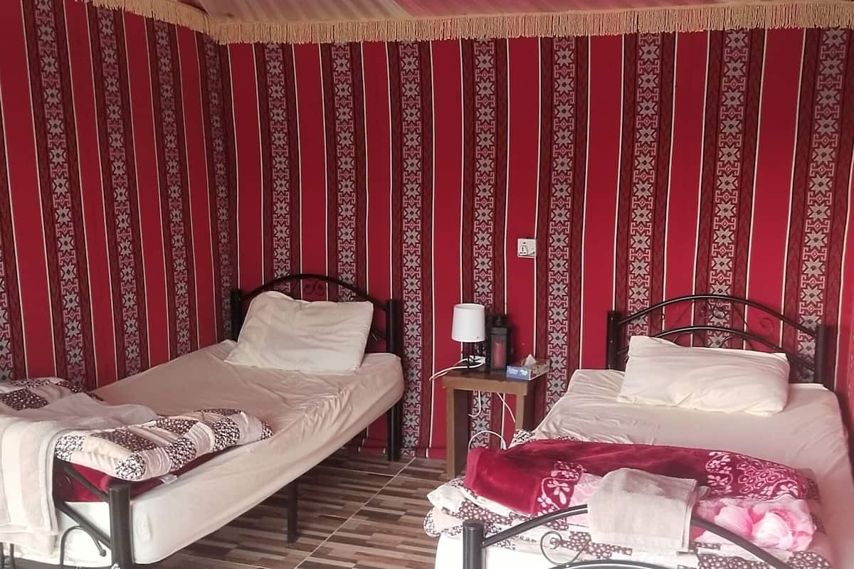 Quarto com duas camas, uma mesa de cabeceira e parede estampada.