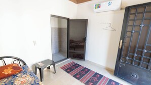 Un dormitori amb un llit, una taula petita, un armari i una porta amb un dibuix decoratiu.